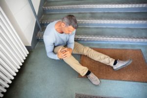 man rubbing his knee in pain and slip and fall