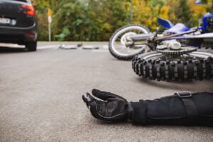 injured motorcyclist lying in the street as a car pulls away