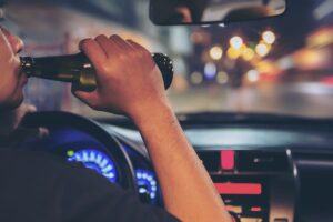 man drinking beer while driving