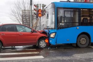 A red car and a blue bus involved in a head-on collision at an intersection.