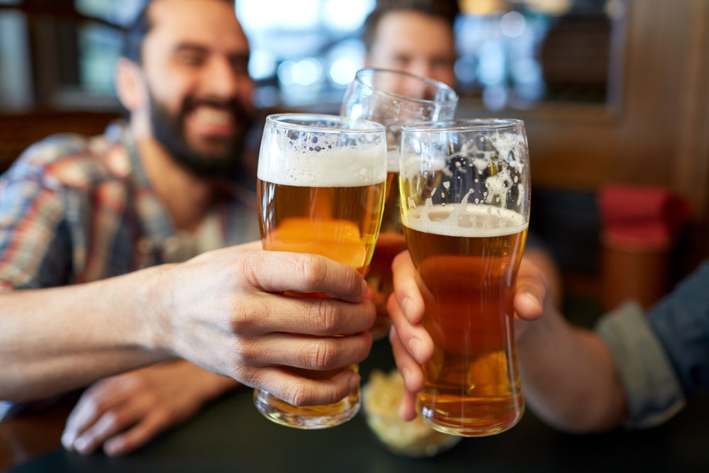 group of men clinking beer glasses together