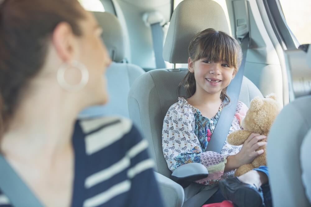 Mother turning and smiling at daughter in back seat of car