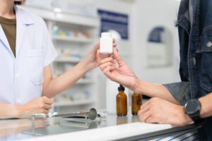 Close up hands of selling female pharmacist and male customer buying medicine in the pharmacy drugstore